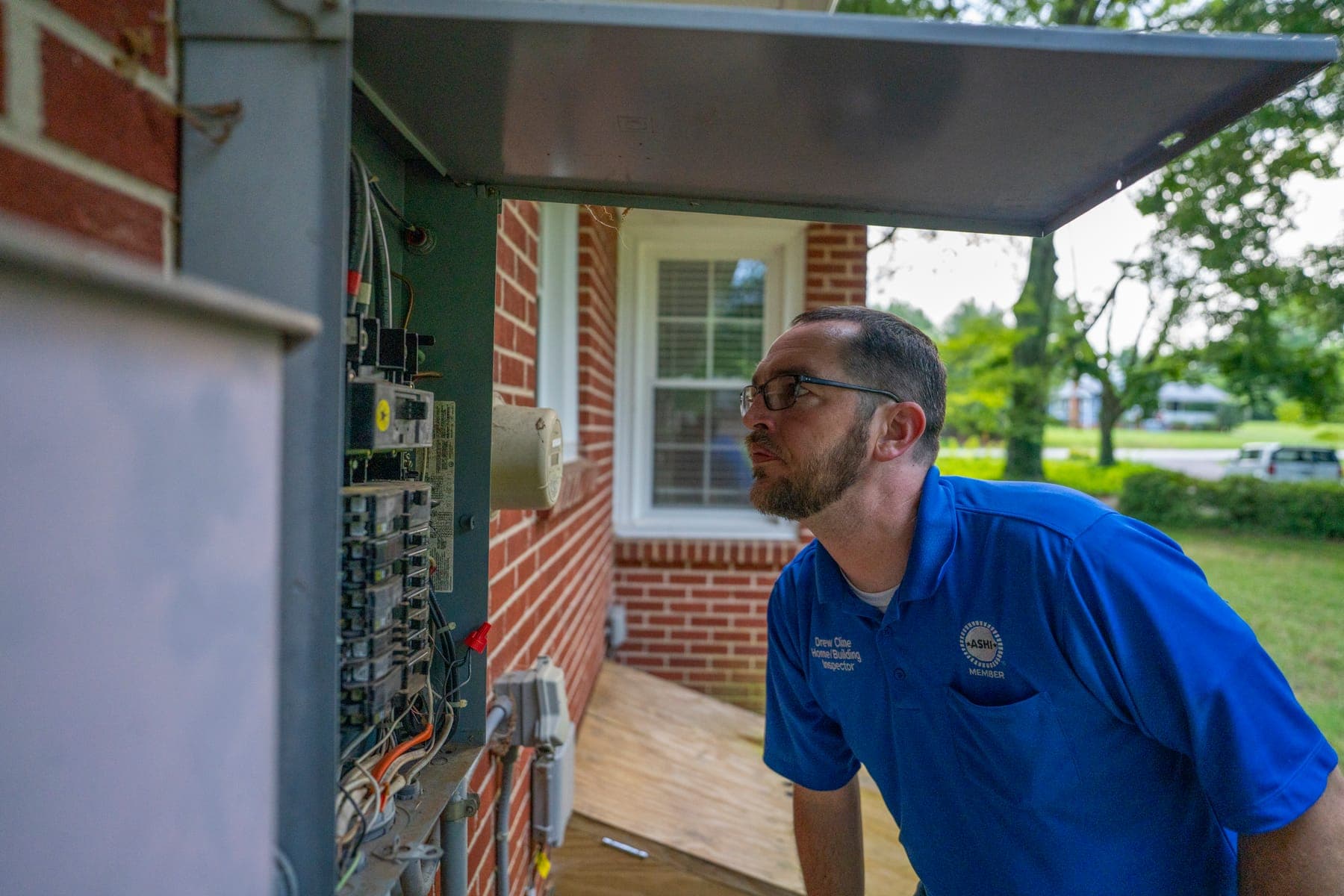 Drew Cline documenting findings at an exterior electrical panel